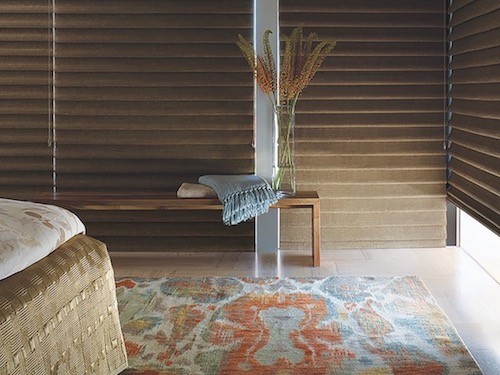 A bedroom with pastel accents in a rug and a throw blanket.